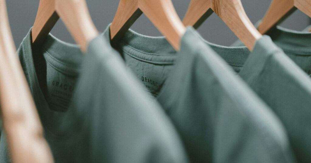 木製ハンガーにかかったグリーンのTシャツ