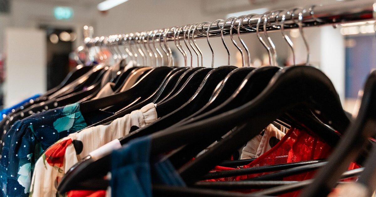 カラフルな柄物ドレスが黒いハンガーにかかったショップ内