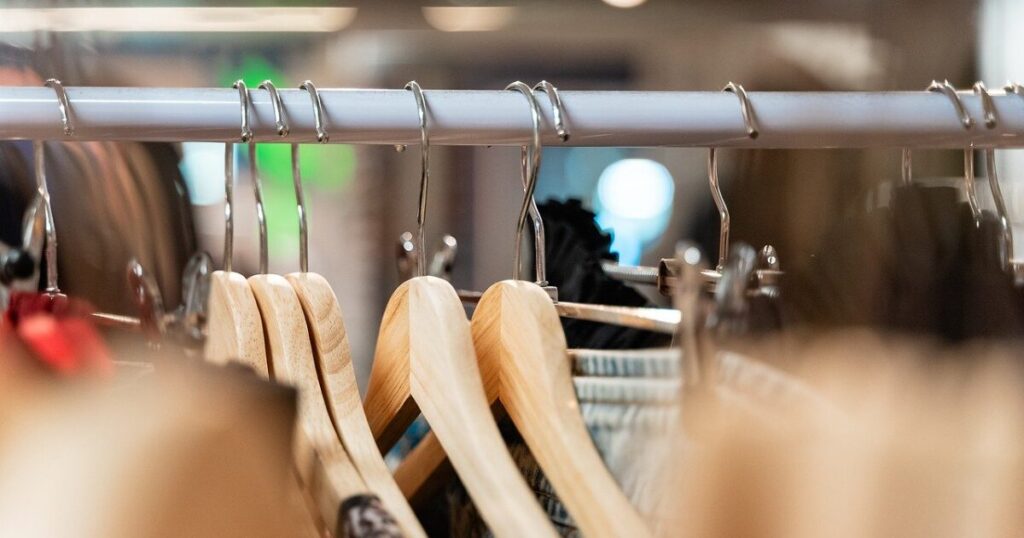 ショップ内のラックに掛けられた木製ハンガーと衣類